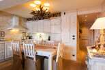 This stunning kitchen boasts a rustic charm with its wooden cabinets and a unique chandelier.
