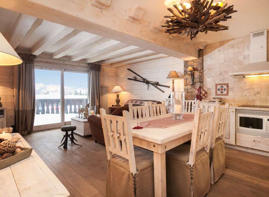 This charming chalet-style interior showcases a cozy living space with rustic wooden beams and flooring.