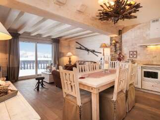 This charming chalet-style interior showcases a cozy living space with rustic wooden beams and flooring.
