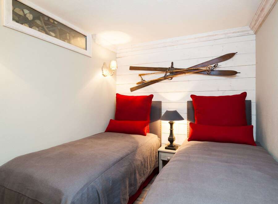 This cozy bedroom features two twin beds with stylish red pillows, perfect for guests or a shared space.