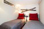 This cozy bedroom features two twin beds with stylish red pillows, perfect for guests or a shared space.