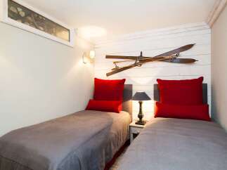 This cozy bedroom features two twin beds with stylish red pillows, perfect for guests or a shared space.