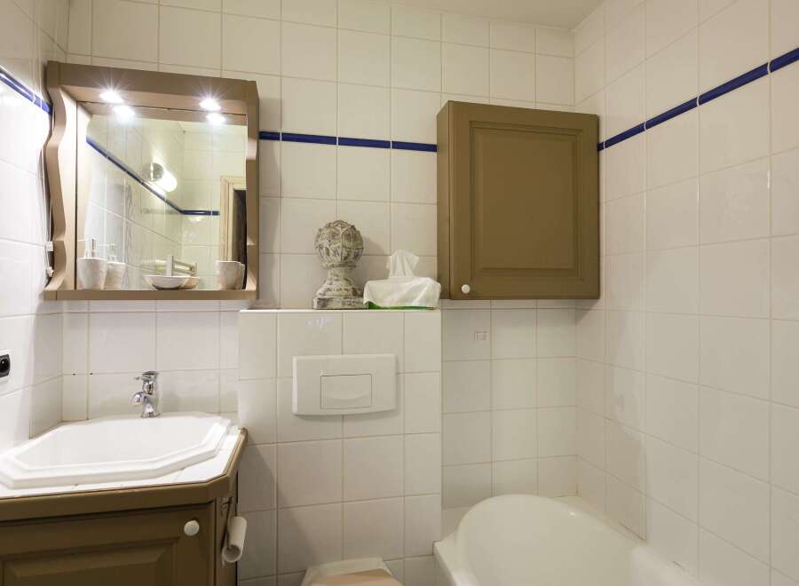 This charming bathroom features a classic design with white tiled walls and a touch of blue trim.