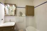 This charming bathroom features a classic design with white tiled walls and a touch of blue trim.