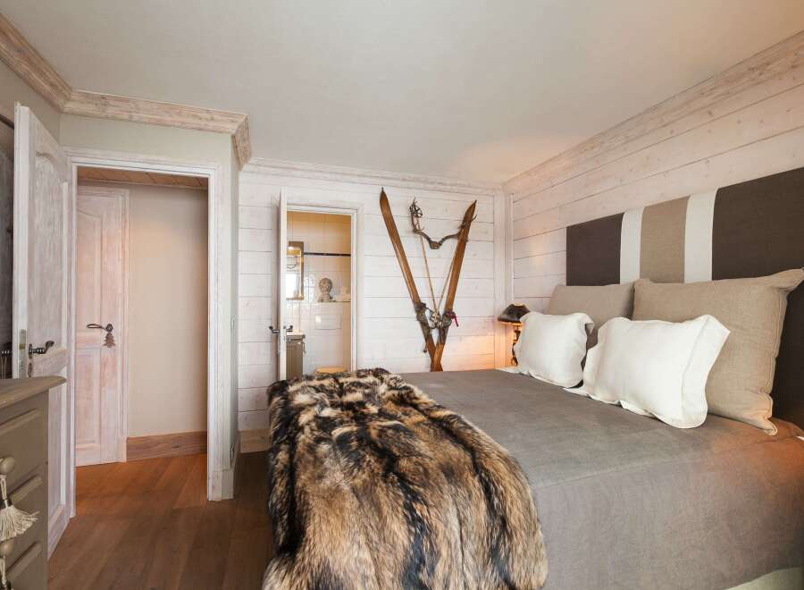 This cozy bedroom features a rustic design with wooden accents and a luxurious fur throw.
