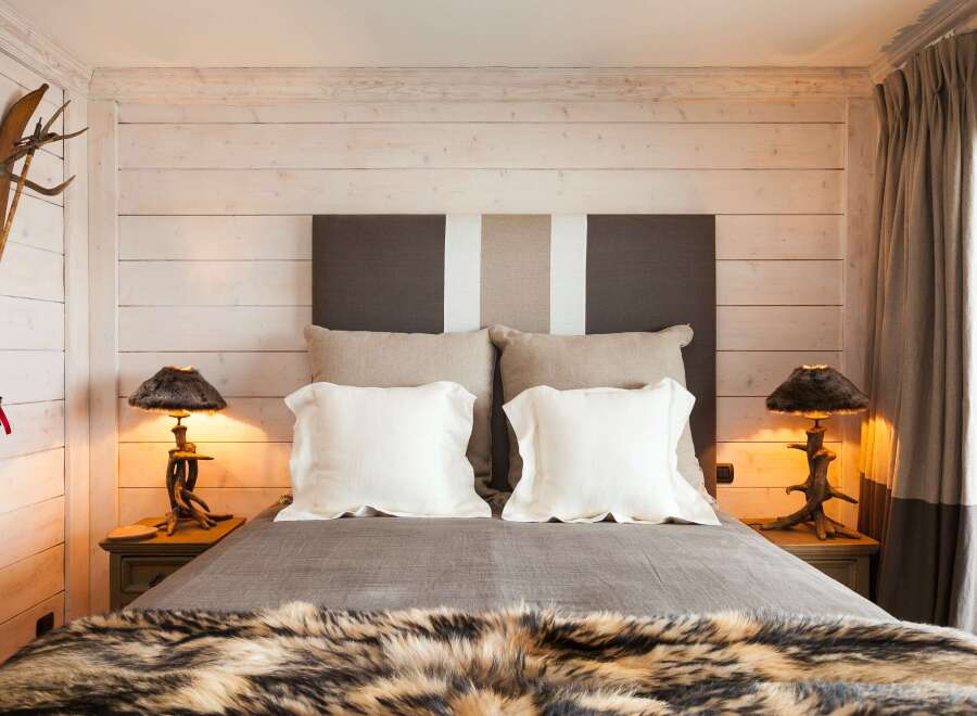 This cozy bedroom features a rustic design with wooden paneling and a luxurious fur throw.