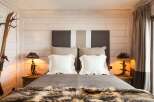 This cozy bedroom features a rustic design with wooden paneling and a luxurious fur throw.