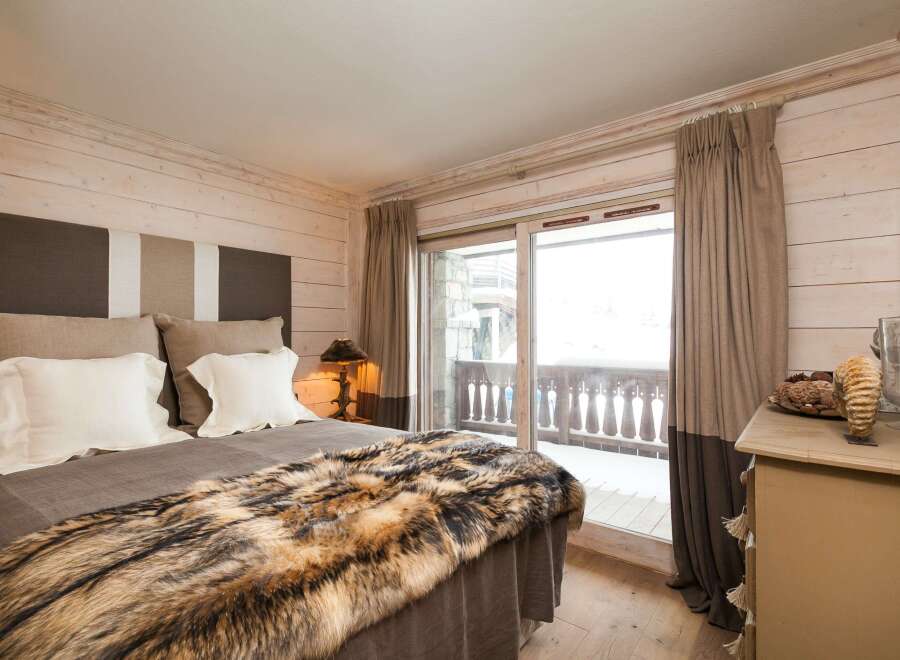 Experience the epitome of luxury in this stunning bedroom, featuring a plush bed adorned with a faux fur throw.