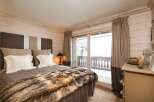 Experience the epitome of luxury in this stunning bedroom, featuring a plush bed adorned with a faux fur throw.