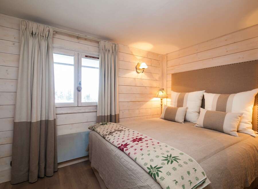 This cozy bedroom features a rustic design with wooden paneling and warm lighting, creating a welcoming atmosphere.