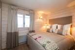 This cozy bedroom features a rustic design with wooden paneling and warm lighting, creating a welcoming atmosphere.