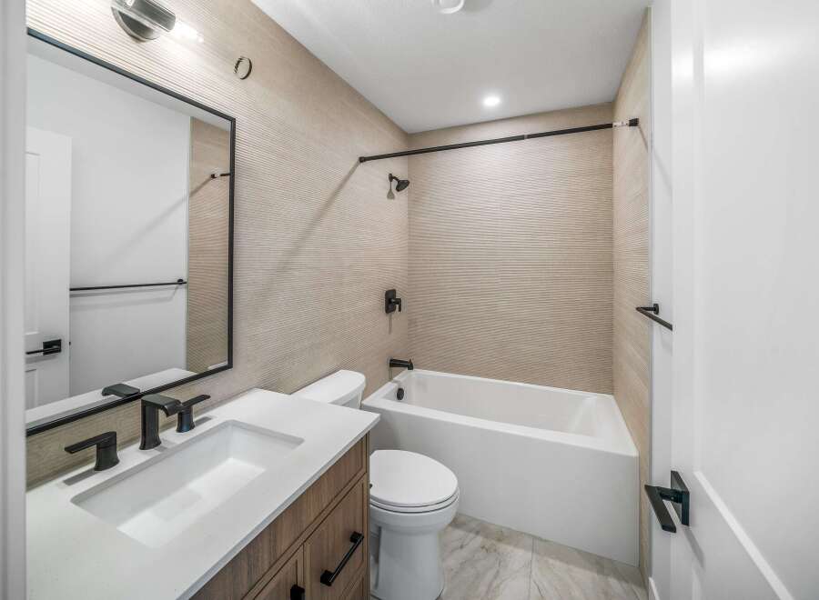 Step into a modern bathroom oasis! This space features a sleek vanity with a pristine white countertop, complemented by a stylish mirror and contemporary fixtures.