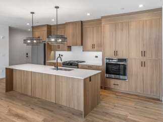 This stunning kitchen boasts modern design with sleek wooden cabinetry and a spacious island.