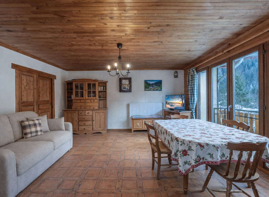 Step into this charming living space, featuring a warm wooden ceiling and inviting ambiance.