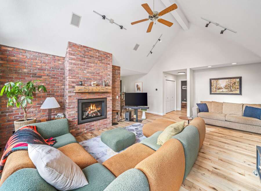 This stunning living room boasts a cozy fireplace with a brick surround, creating a warm and inviting atmosphere.