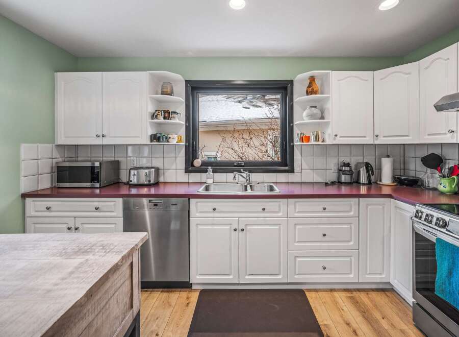 This stunning kitchen boasts a modern design with sleek white cabinetry and a vibrant red countertop, creating a stylish and inviting atmosphere.