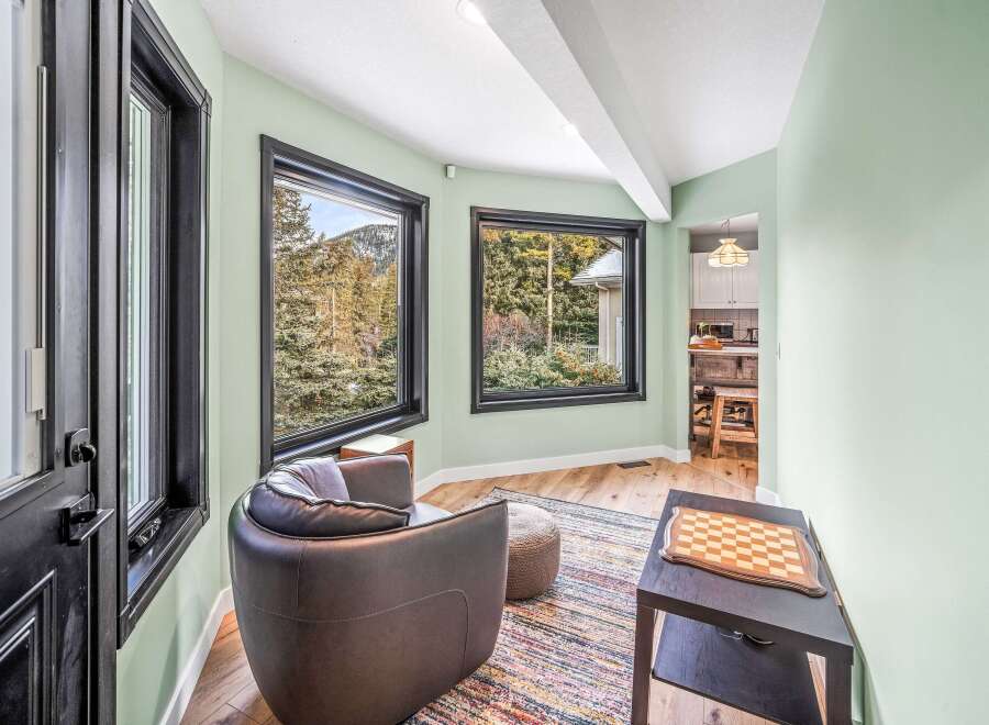 This stunning property boasts a cozy reading nook with a comfortable armchair and a vibrant rug.
