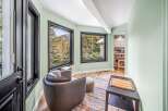 This stunning property boasts a cozy reading nook with a comfortable armchair and a vibrant rug.