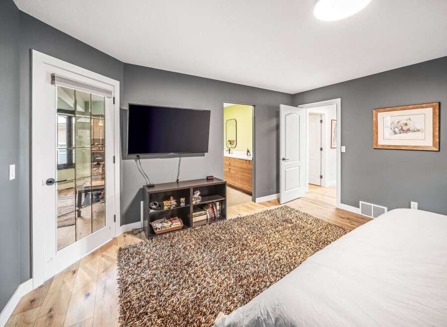 Step into this inviting bedroom, featuring a sleek, mounted TV and a cozy, textured rug.