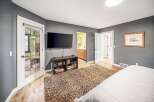 Step into this inviting bedroom, featuring a sleek, mounted TV and a cozy, textured rug.