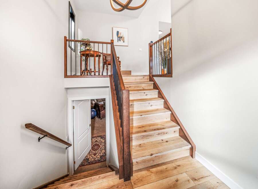 This stunning property features a beautifully designed staircase with wooden steps and a matching handrail, creating a warm and inviting atmosphere.