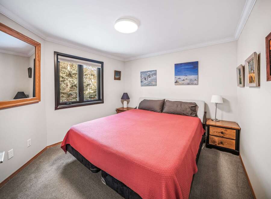 This cozy bedroom features a comfortable bed with a vibrant red cover, perfect for a relaxing retreat.