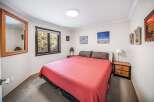 This cozy bedroom features a comfortable bed with a vibrant red cover, perfect for a relaxing retreat.