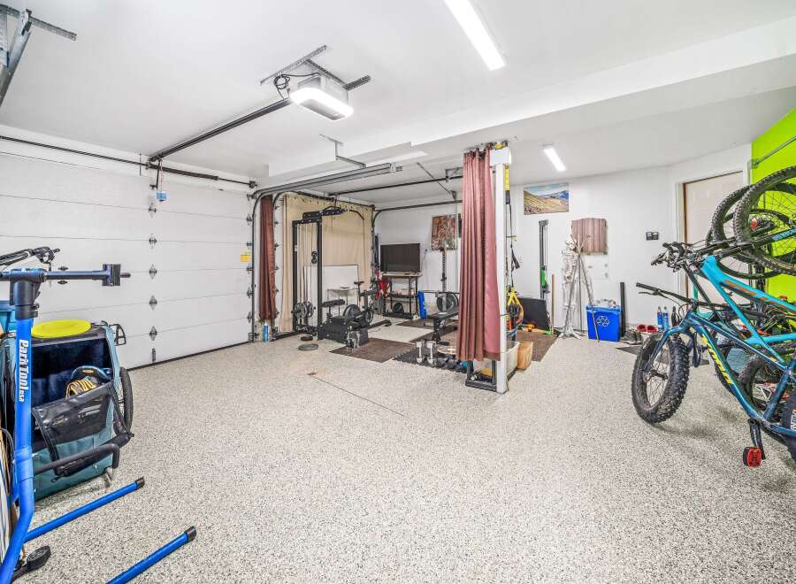 This spacious garage has been transformed into a functional home gym and storage space.
