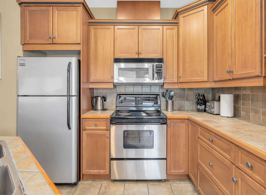 This stunning kitchen boasts beautiful wooden cabinetry and modern stainless steel appliances, creating a warm and inviting atmosphere.