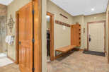 Step into this inviting entryway, showcasing beautiful wooden doors and a warm, neutral color palette.