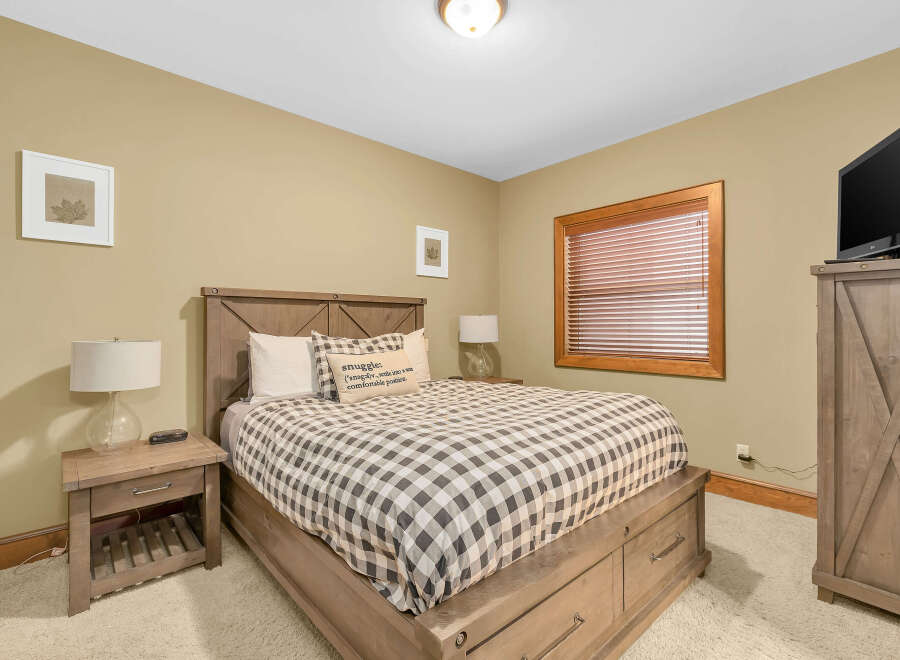 This cozy bedroom features a comfortable bed with a stylish checkered comforter and a decorative pillow, perfect for a relaxing retreat.