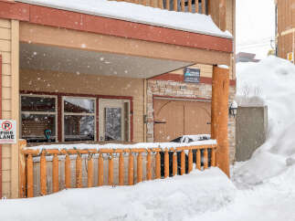 This charming property features a cozy porch, perfect for enjoying snowy mountain views.