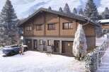 Discover your dream alpine retreat! This stunning property boasts a modern design with a warm, inviting wooden facade and a stone base.