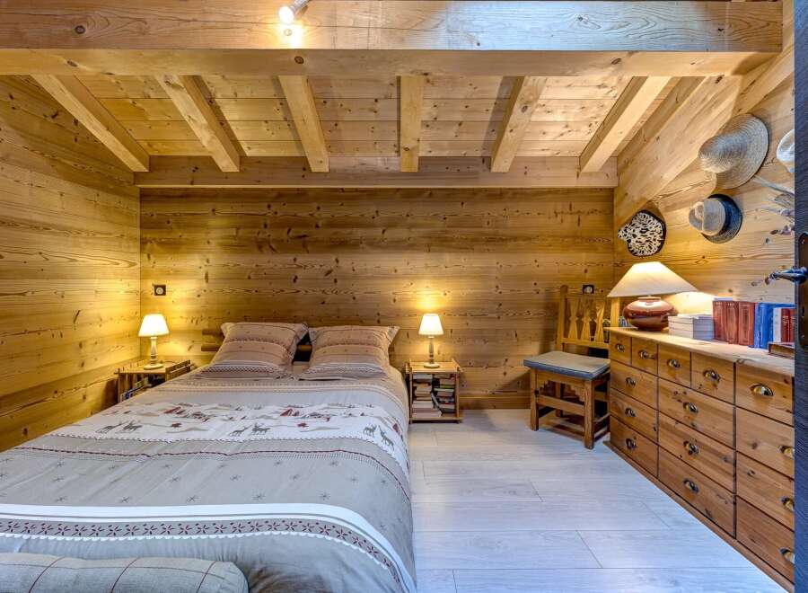 Step into a cozy bedroom retreat, featuring warm wooden walls and ceiling that create a rustic ambiance.
