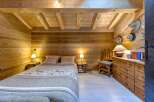 Step into a cozy bedroom retreat, featuring warm wooden walls and ceiling that create a rustic ambiance.
