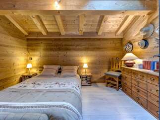 Step into a cozy bedroom retreat, featuring warm wooden walls and ceiling that create a rustic ambiance.