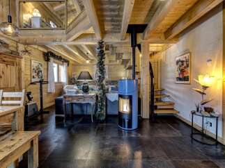 This stunning property features a cozy living space with exposed wooden beams and a modern fireplace, creating a warm and inviting atmosphere.