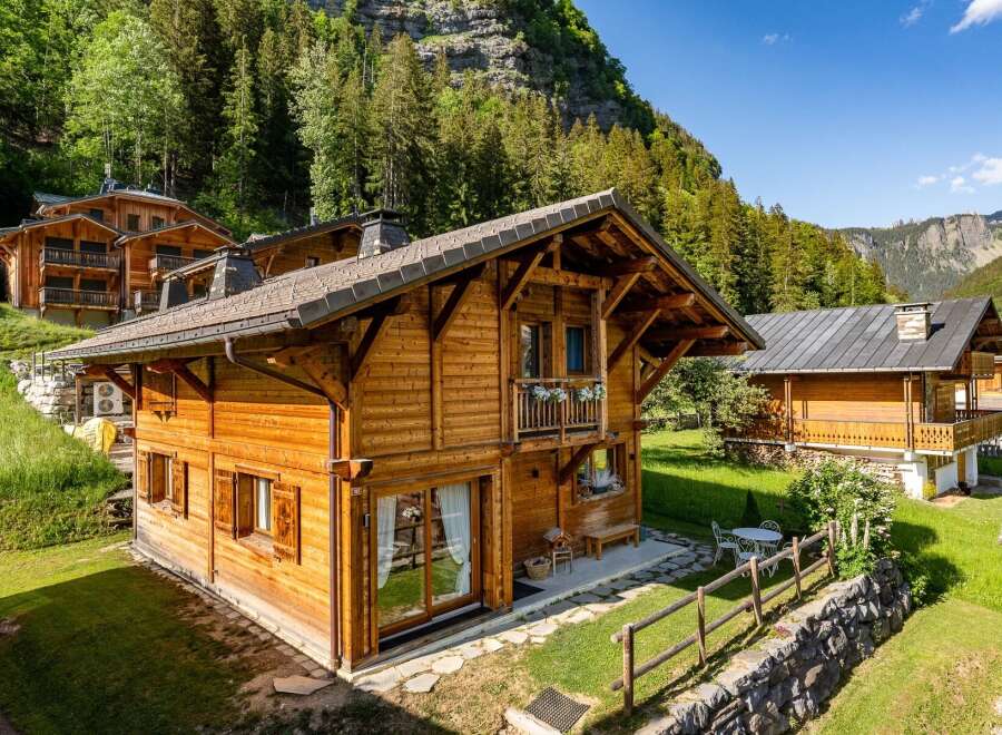 Experience the charm of alpine living in this stunning wooden chalet nestled amidst lush greenery and majestic mountains.