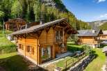Experience the charm of alpine living in this stunning wooden chalet nestled amidst lush greenery and majestic mountains.