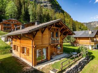 Experience the charm of alpine living in this stunning wooden chalet nestled amidst lush greenery and majestic mountains.