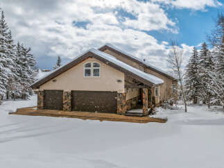 This stunning property boasts a beautiful exterior with a snow-covered roof and surrounding landscape.