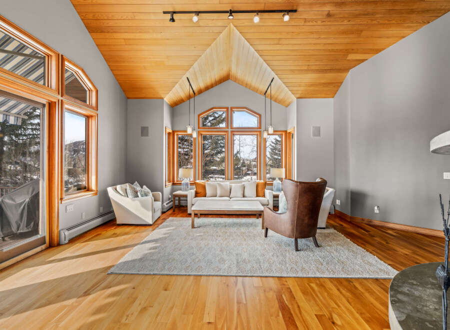 This stunning living room boasts a vaulted wooden ceiling and expansive windows that flood the space with natural light.