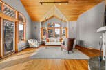 This stunning living room boasts a vaulted wooden ceiling and expansive windows that flood the space with natural light.
