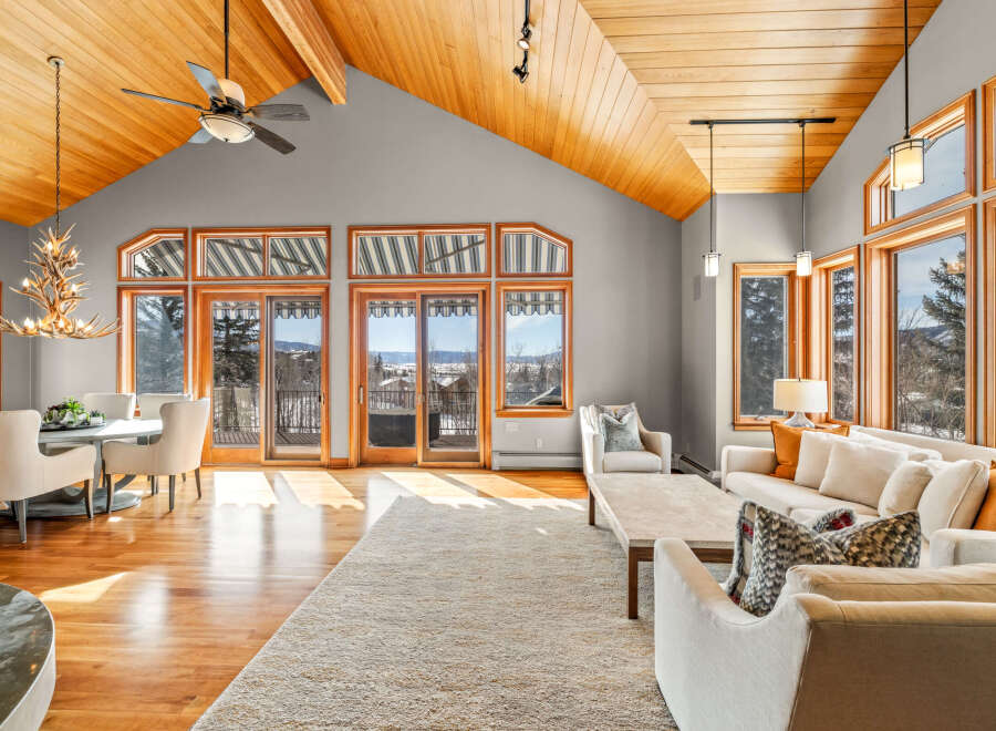 Experience luxury living in this stunning property featuring a spacious living area with a vaulted wood ceiling and large windows.