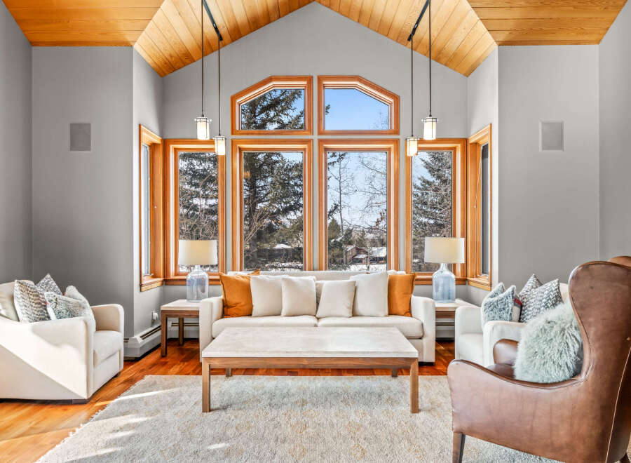 Step into luxury with this stunning living room, boasting a vaulted wooden ceiling and expansive windows that frame breathtaking views.