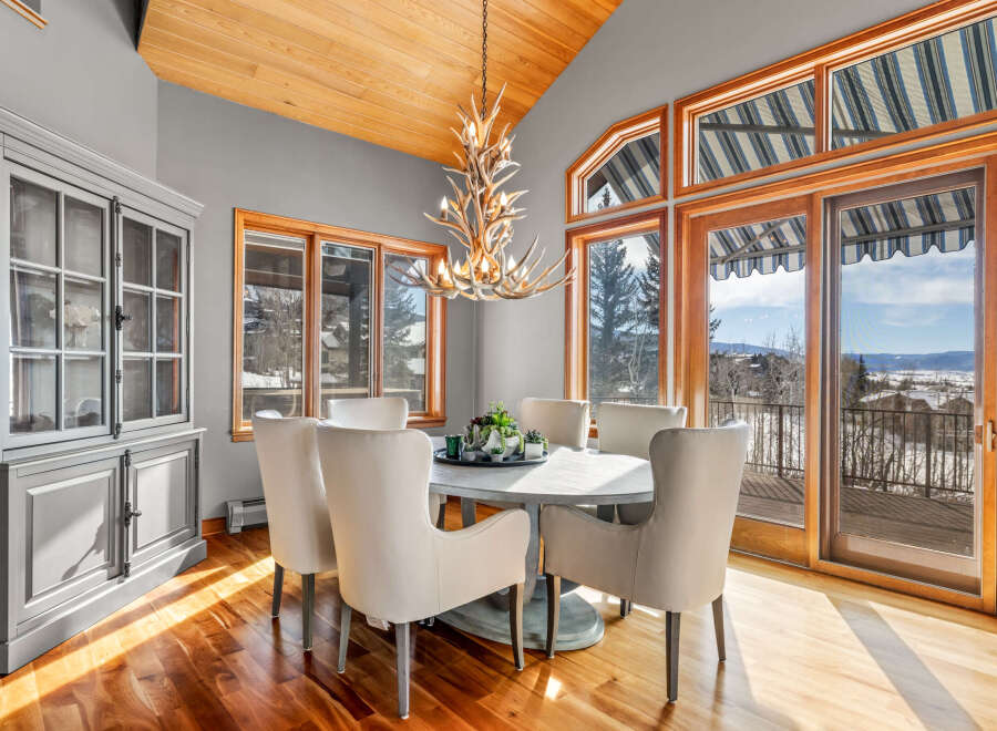 This stunning dining room boasts a unique antler chandelier, creating a focal point above the elegant round dining table.