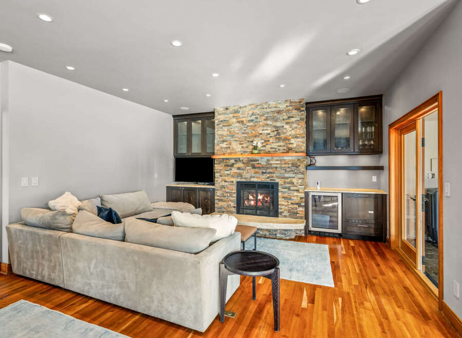 This stunning living room boasts a cozy fireplace with a stone facade, perfect for those chilly evenings.
