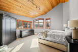 This stunning bedroom boasts a warm, inviting ambiance with its wooden ceiling and ample natural light.