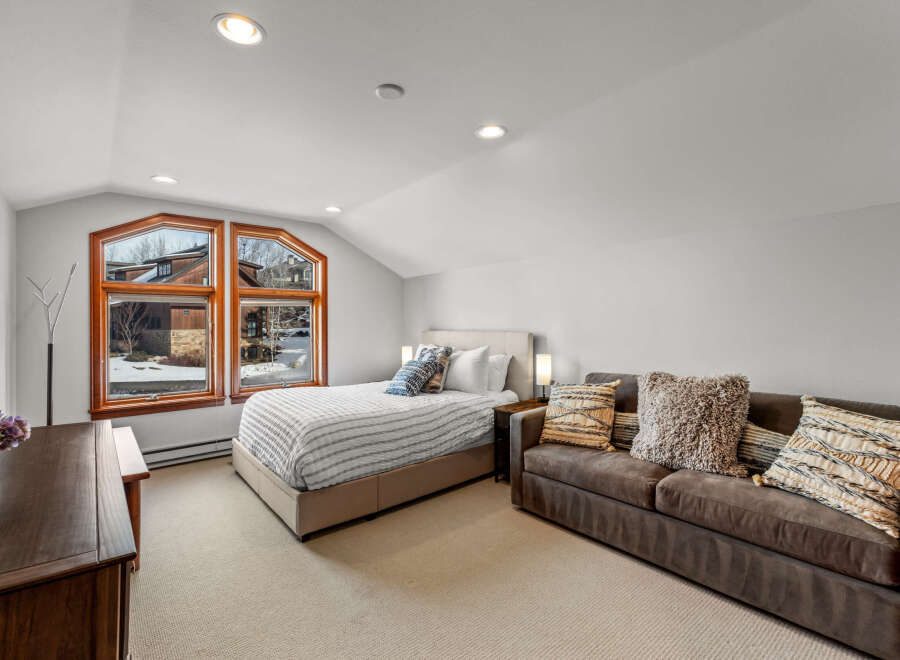 This cozy bedroom features a comfortable bed, a stylish sofa, and a large window that offers stunning views.