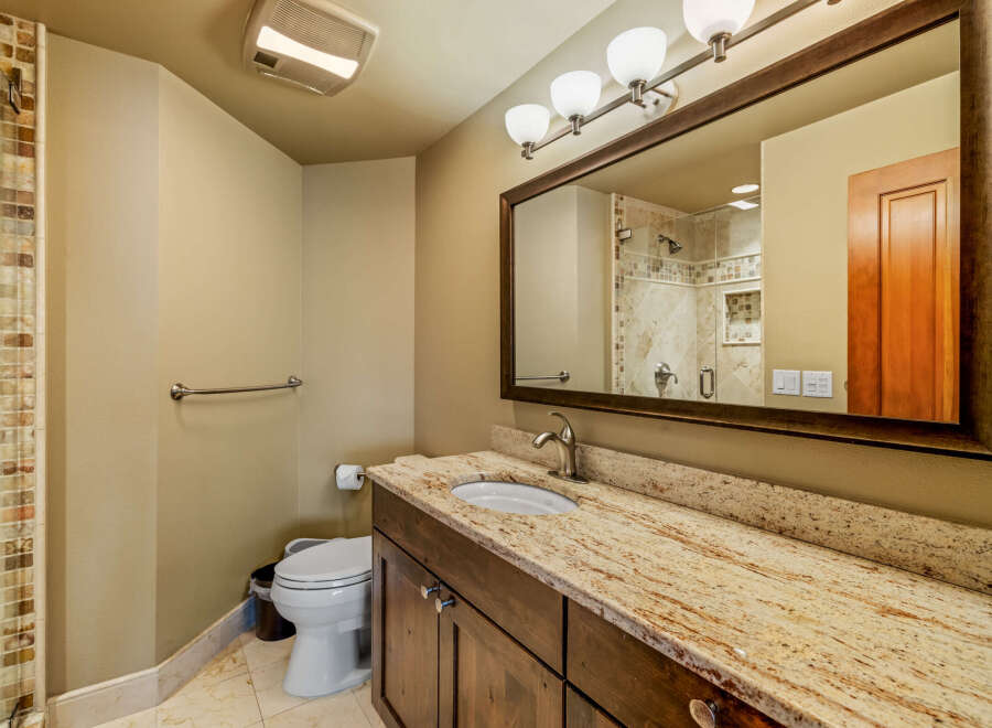 This stunning bathroom boasts a luxurious granite countertop and a stylish wooden vanity, offering both elegance and functionality.